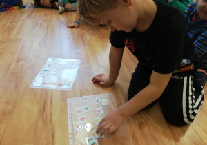 Chłopiec układa jesienne symbole zgodnie z podanym kodem